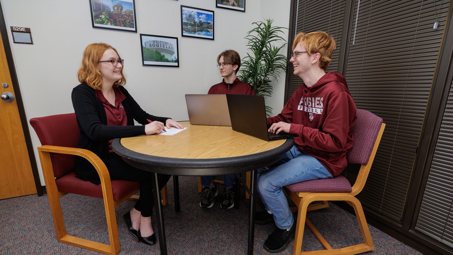An academic advisor meets with two students.