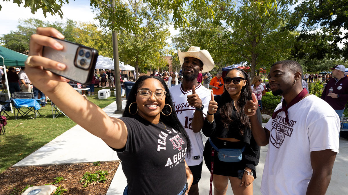 Four Texas A&M studdents pose for a selfie while tailgating at an 91短视频 football game