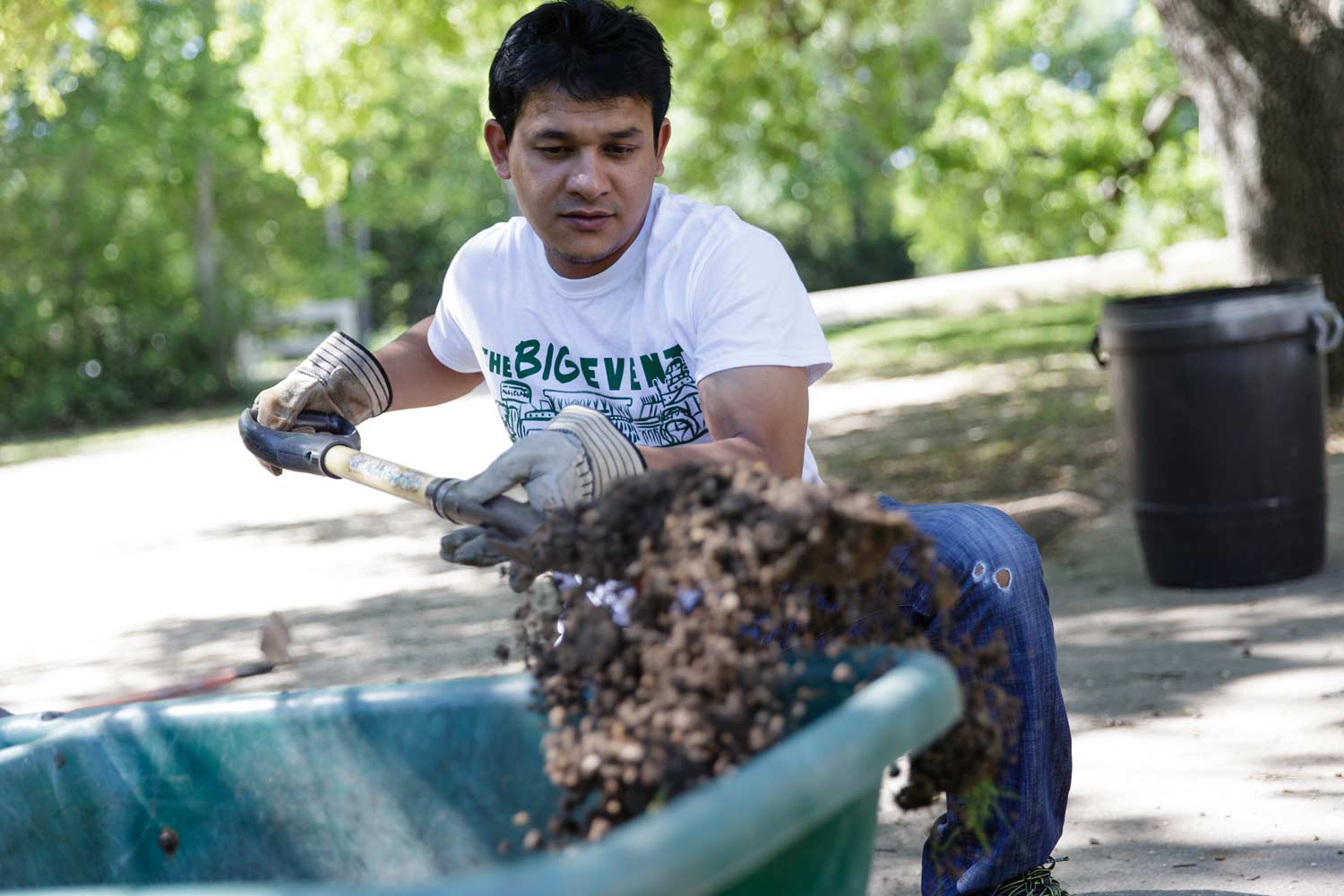 Student shovels dirt into a wheelbarrow for Big Event