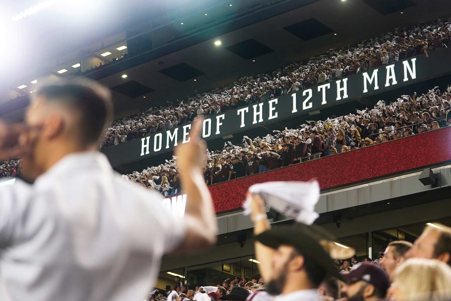Home of the 12th man sign in Kyle Field with a yell leader partially in the front