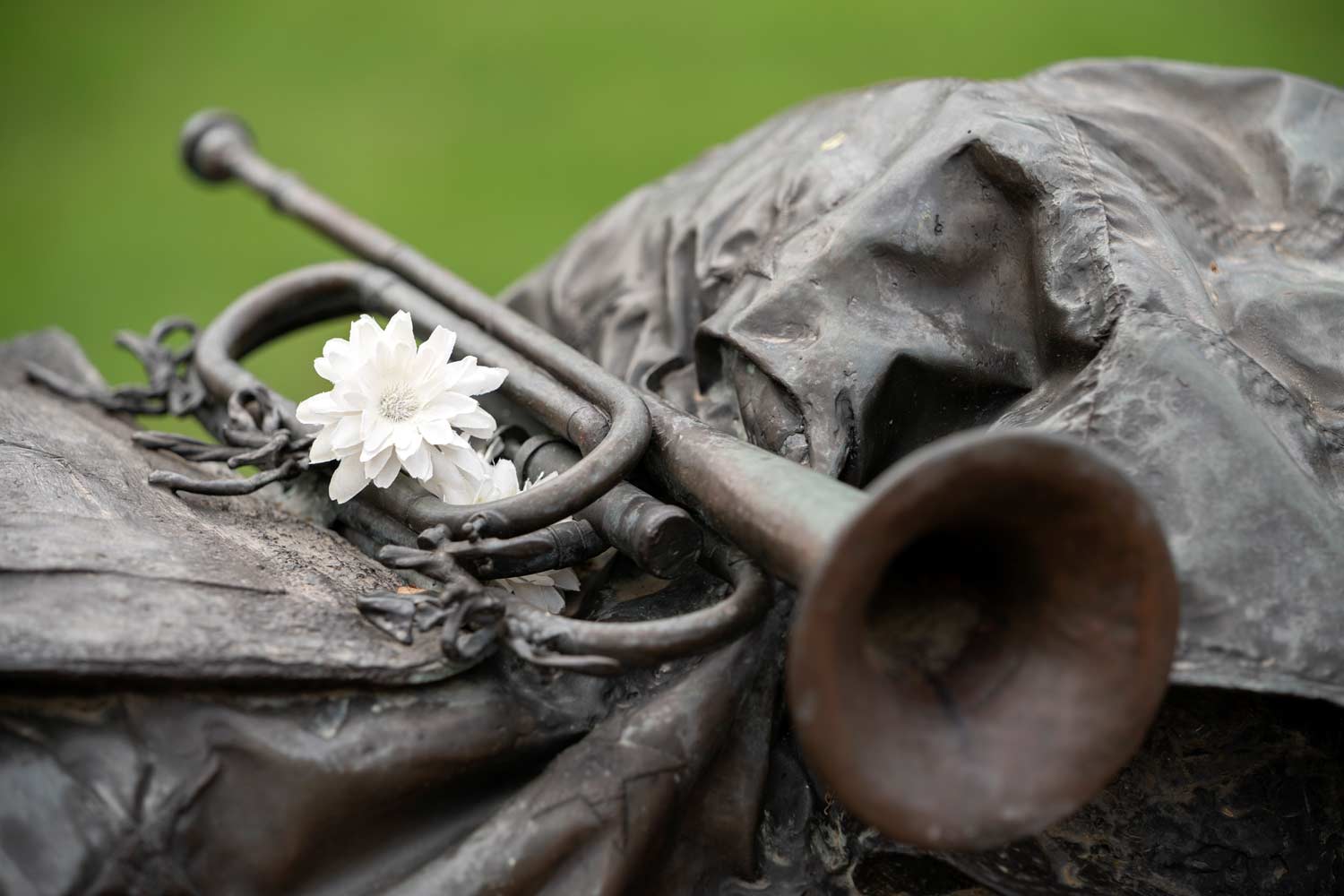 Silver Taps statue on campus, a bugle resting on top of a blanket, a student has placed a flower with it in rememberance of fallen students