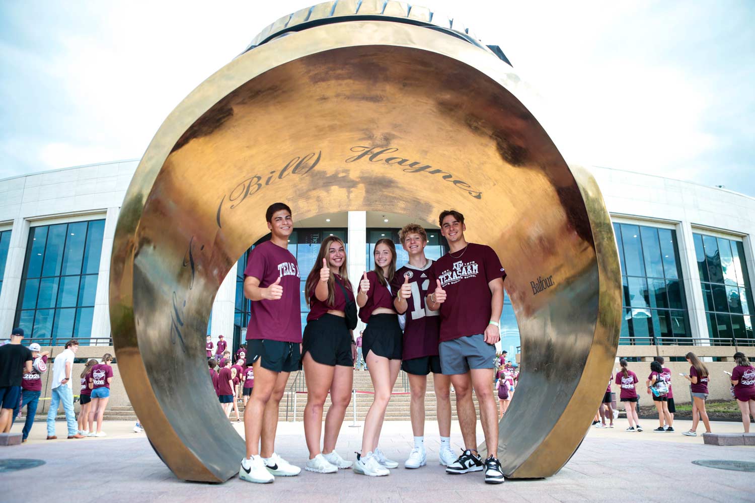 Texas A&M University students posing under the Association of Former Students Ring Statue